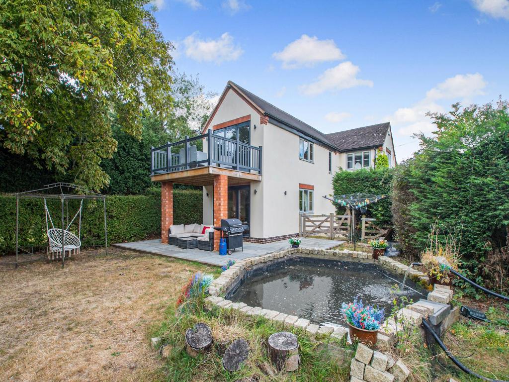 a house with a pond in the yard at Lovetts Bridge Cottage in Atherstone