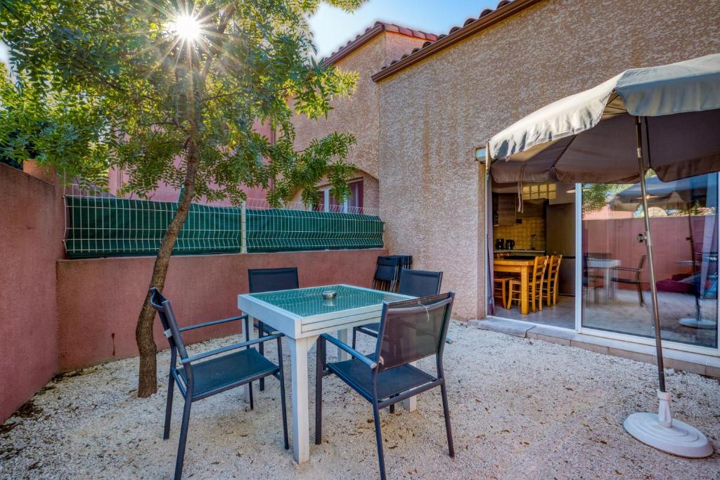 a patio with a table and chairs and a tree at Gîte Terres Rouges - Lac Salagou in Le Bosc