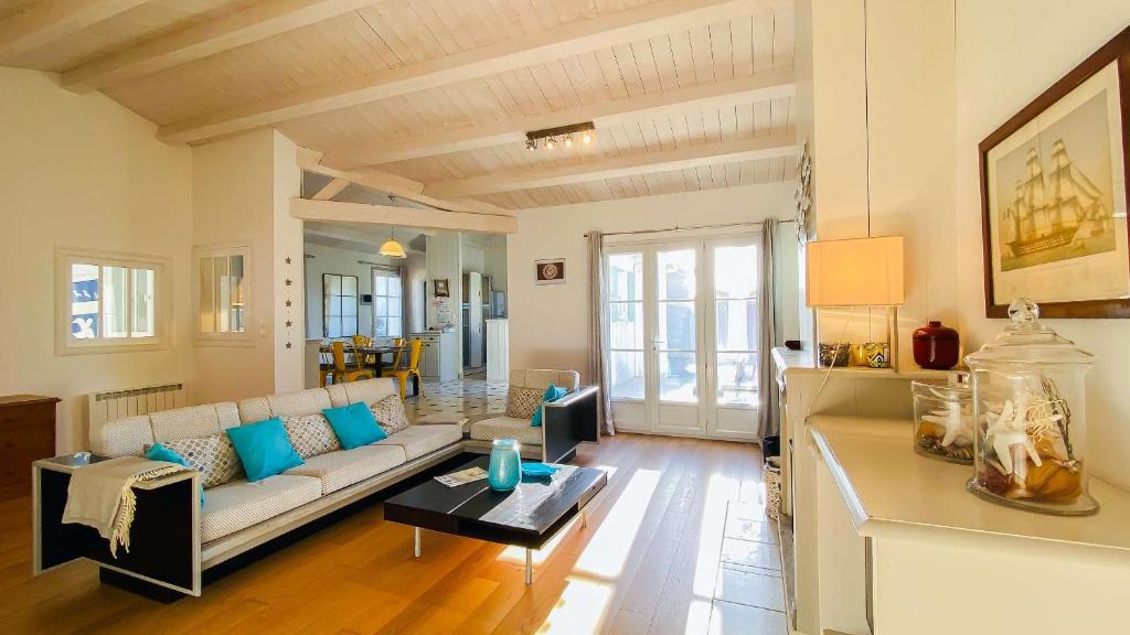 ein Wohnzimmer mit Sofa und Tisch in der Unterkunft Villa récente de style réthais avec piscine chauffée et jardin paysager in Le Bois-Plage-en-Ré