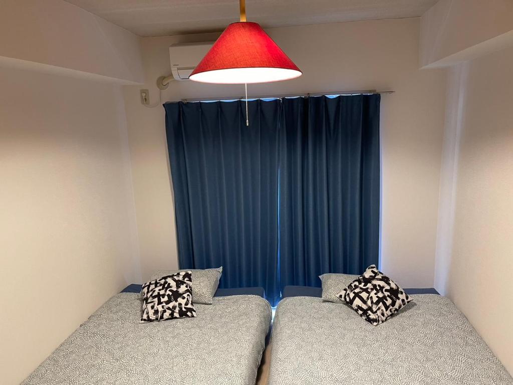 twee bedden in een kamer met een blauw gordijn bij KT-HouSe FUKUOKA ツイン in Fukuoka