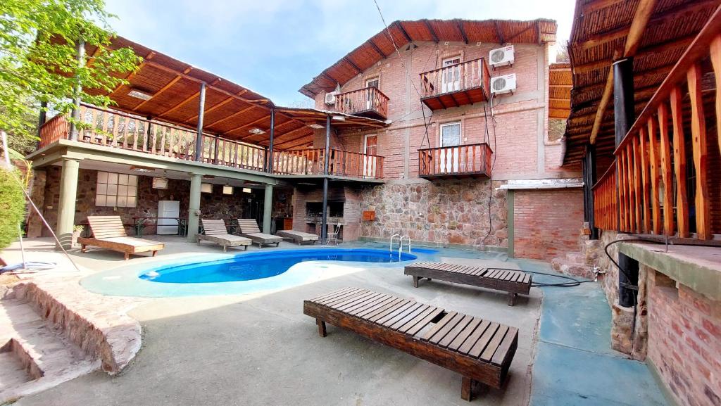 a building with a pool and a patio with benches at Complejo Turístico Hugo Ávila in La Rioja