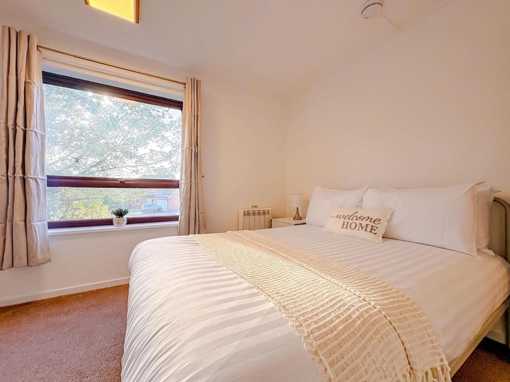 a bedroom with a large white bed with a window at Russet Grove in Earlham