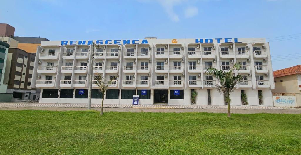 Un gran edificio blanco con un hotel en la parte superior. en Atlântico Sul Renascença Hotel, en Laguna