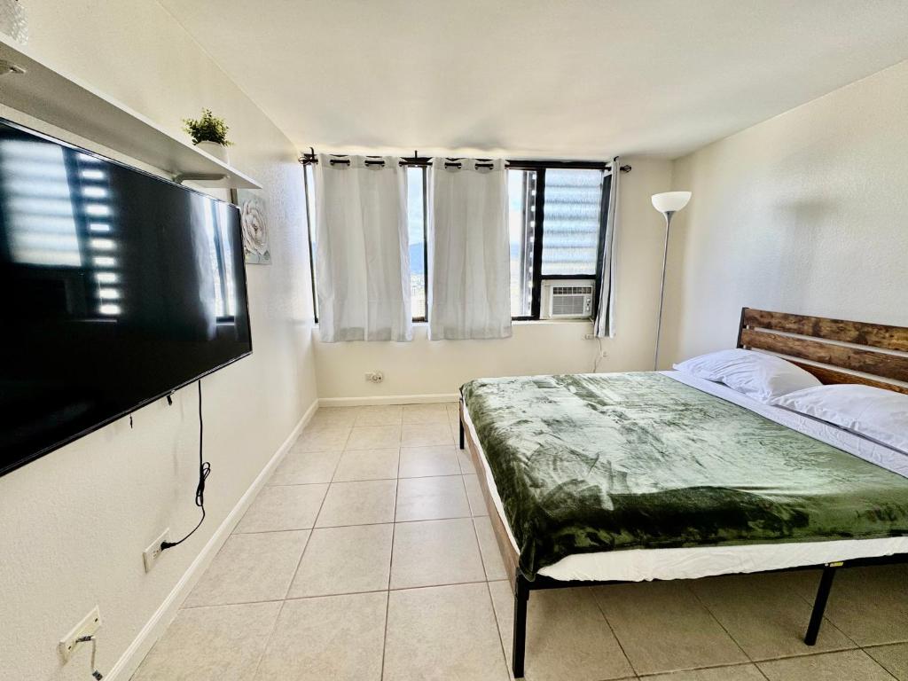 a bedroom with a bed and a flat screen tv at Waikiki Seaside Monarch Paradise Hotel Room Greenery Mountain View in Honolulu
