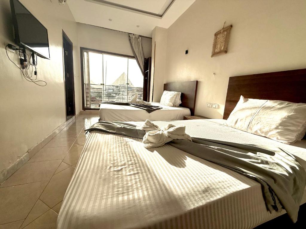 two beds in a room with a large window at Continental Pyramids Terrace Hotel in Cairo