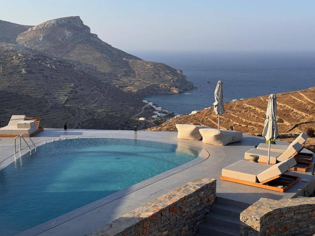 une piscine avec chaises et parasols et l'océan dans l'établissement Pentanemi Folegandros, à Áno Meriá