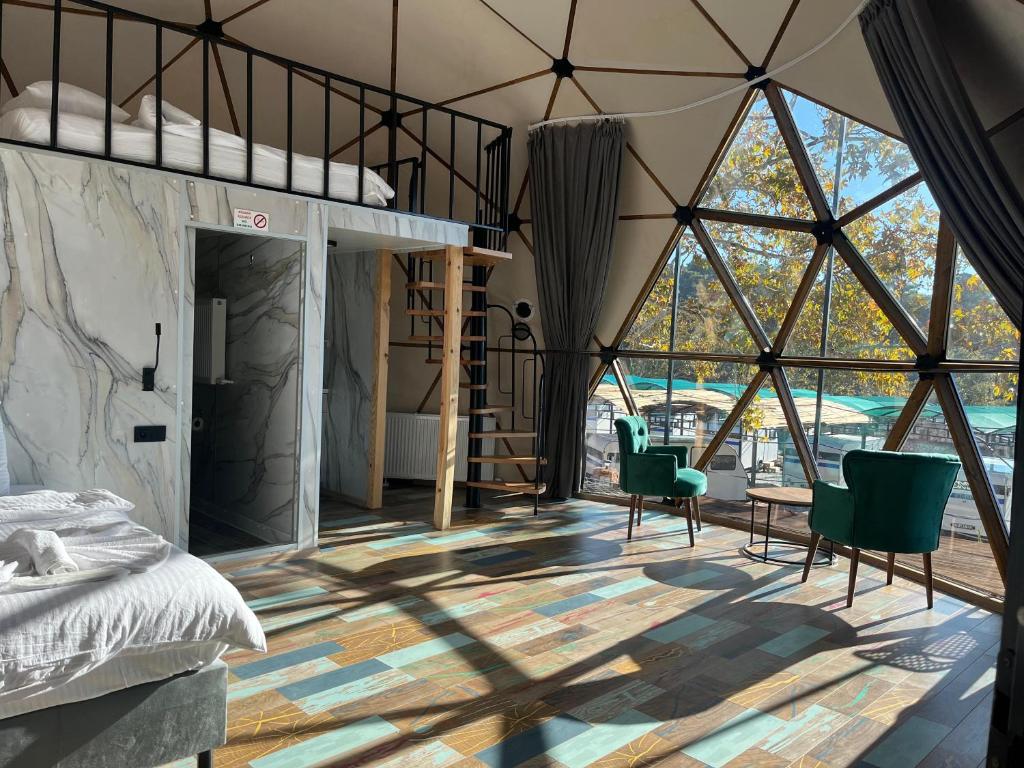 a bedroom with a bed and chairs in a room with large windows at Mas Kazdağı Glamping in Edremit