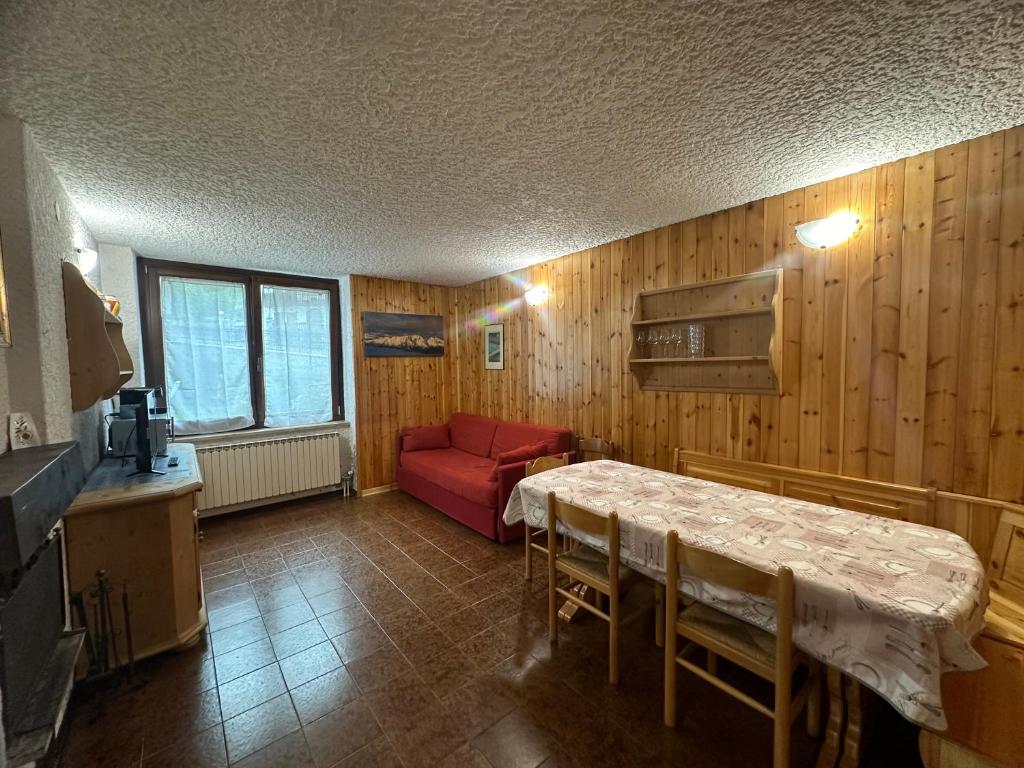 a living room with a table and a red couch at Dimaro-Folgarida Apartment in Monclassico