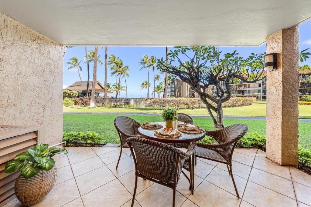 a table and chairs on a patio with a view at Papakea K103 · PK K103 Ocean views Condo | Lanai + AC + Pool in Kaanapali