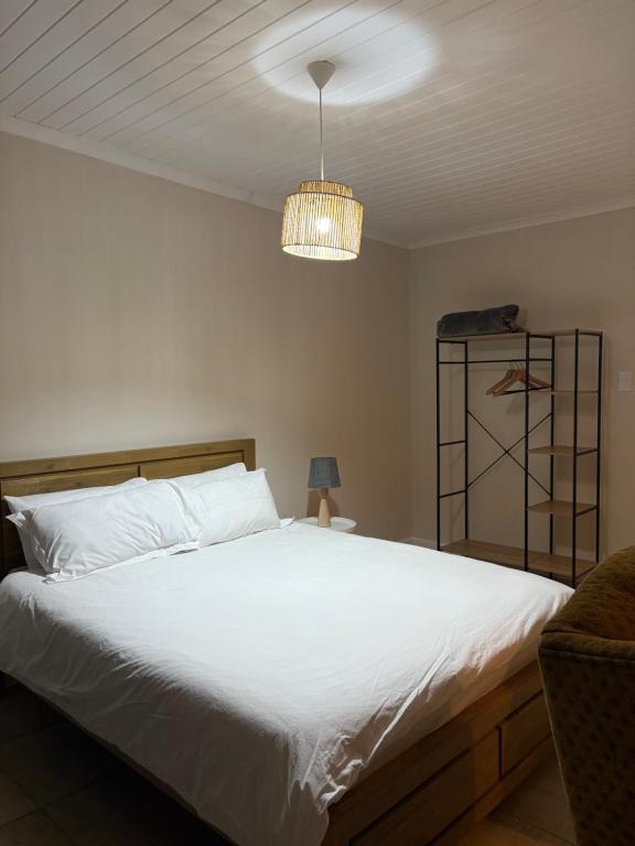 a bedroom with a white bed and a chandelier at Worcester accommodation Putt and Stay in Worcester
