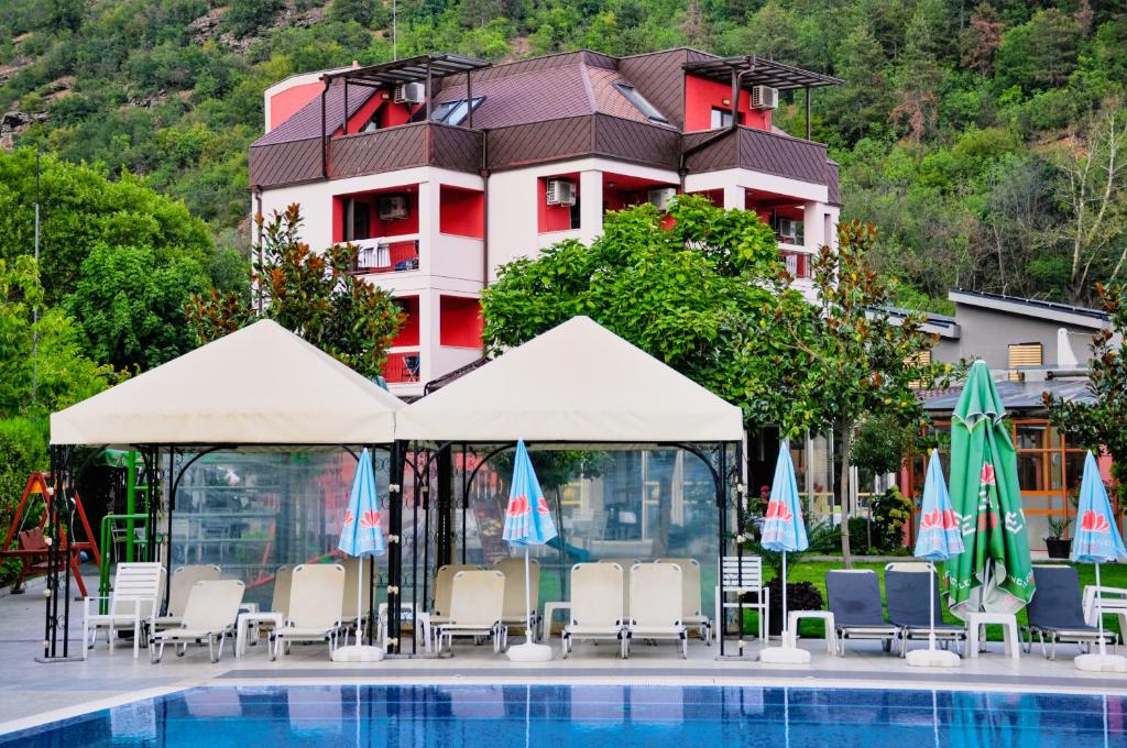 a hotel with a pool and chairs and umbrellas at Elegance Spa Hotel in Ognyanovo