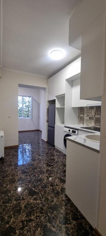 Tskhaltubo Spa Resort Apartments في Itʼkhvisi: مطبخ مع دواليب بيضاء وأرضية من الرخام الأسود