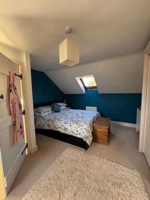 a bedroom with a bed and a blue wall at Millers Barn in Farthinghoe