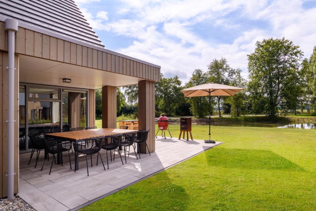 a patio with a table and chairs and an umbrella at Dormio Resort De Hondsrug in Gasselte
