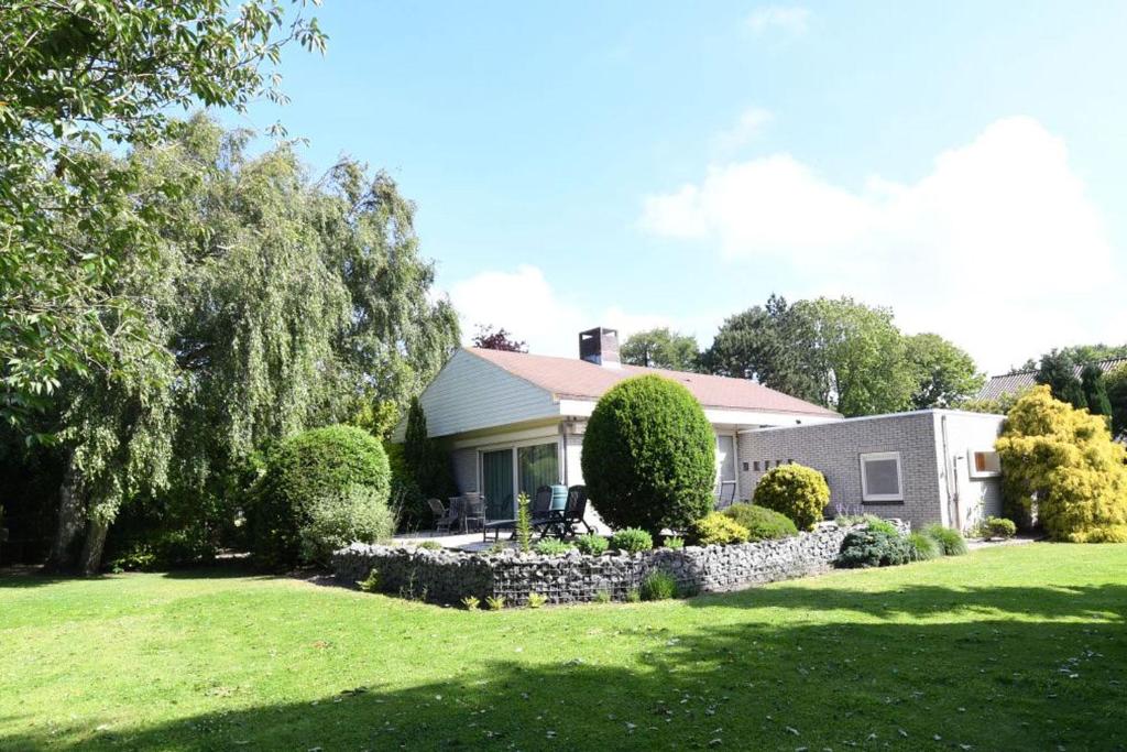 ein Haus mit einem Hof mit einer Steinmauer in der Unterkunft Vrijvakantiehuis Rooistrand in Burgh Haamstede