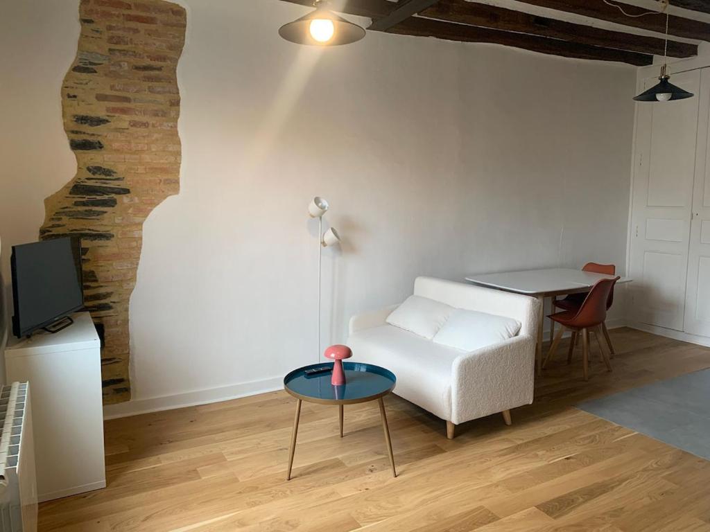 a living room with a white couch and a table at Le Sauge in Angers