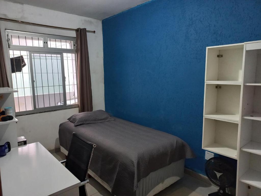 a bedroom with a bed and a blue wall at Caso 3 in São José