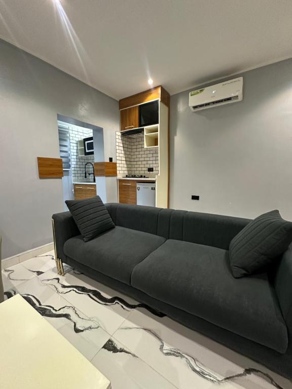 Una sala de estar con un sofá negro y una cocina. en Apartment 5, en Abuja