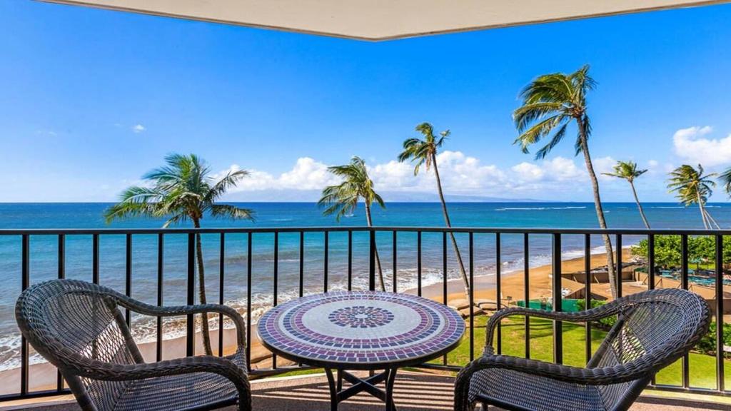 a balcony with a table and chairs and the beach at Valley Isle 407 · VI 407 BeachFront Studio w Pool in Kahana