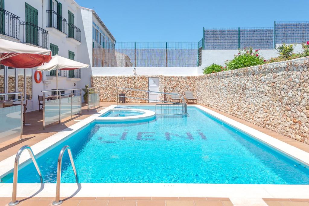 a large swimming pool in a building with a building at Hotel Jeni & Restaurant in Es Mercadal