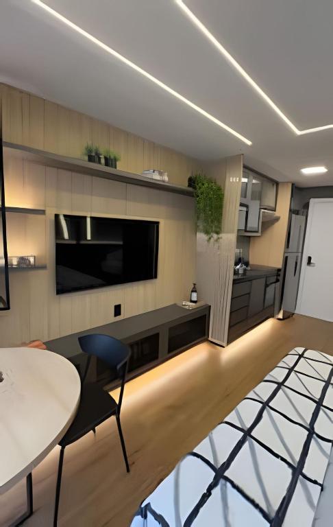 a living room with a large television and a table and chairs at 602 - Estúdio elegante com piscina e academia in Sao Paulo