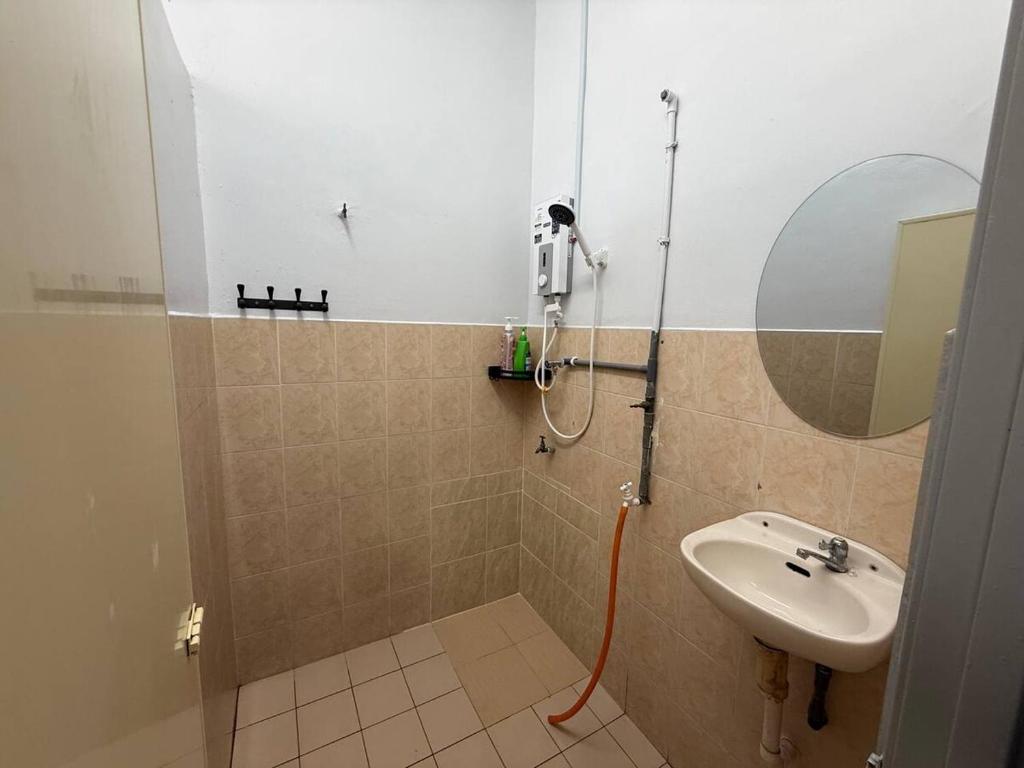 a bathroom with a shower with a sink and a mirror at Wareesha Homestay, Corner Lot With Netflix in Padang Serai