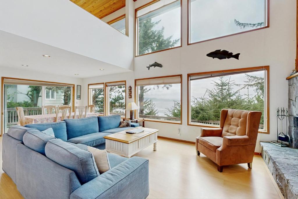 a living room with a blue couch and chairs and windows at Cliffside Serenity in Oceanside