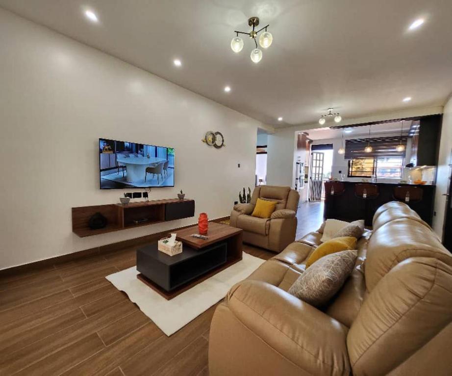 a living room with a couch and a tv at Kisaasi Luxury Apartment in Kampala