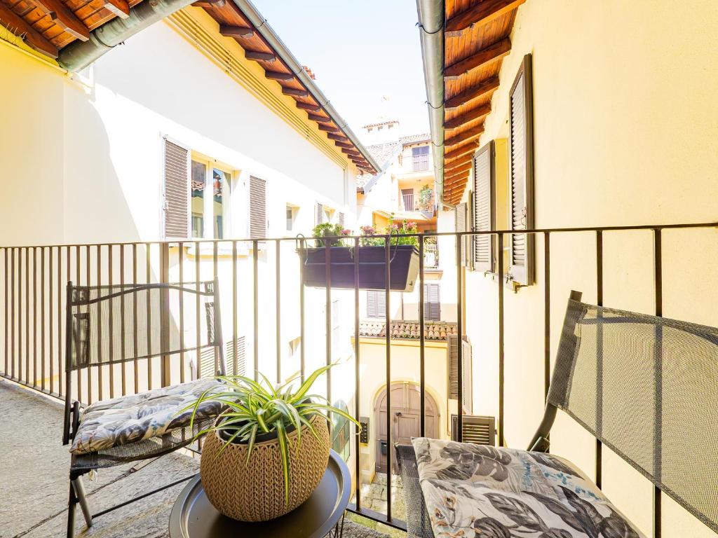 a balcony with two chairs and a table with a plant at Center House Via Anghileri in Lecco