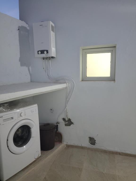 a laundry room with a washing machine and a window at Mechi House in Djerba