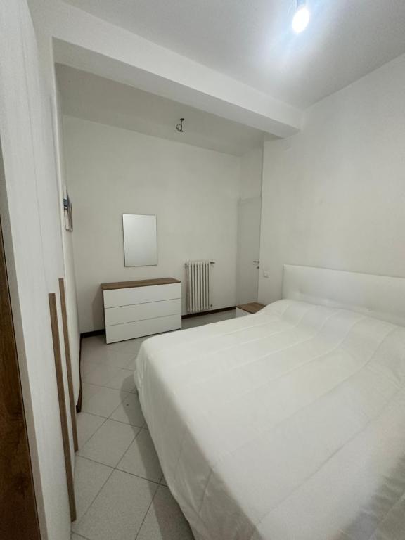 een witte slaapkamer met een groot wit bed en een kast bij Forato Holiday Appartament in Marina di Pietrasanta