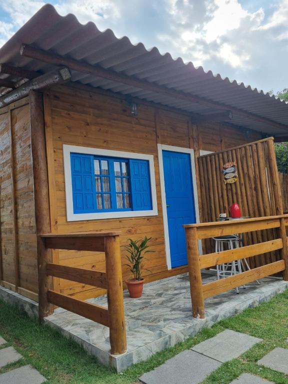 a log cabin with blue windows and a porch at Cedro Rosa in Guarapari