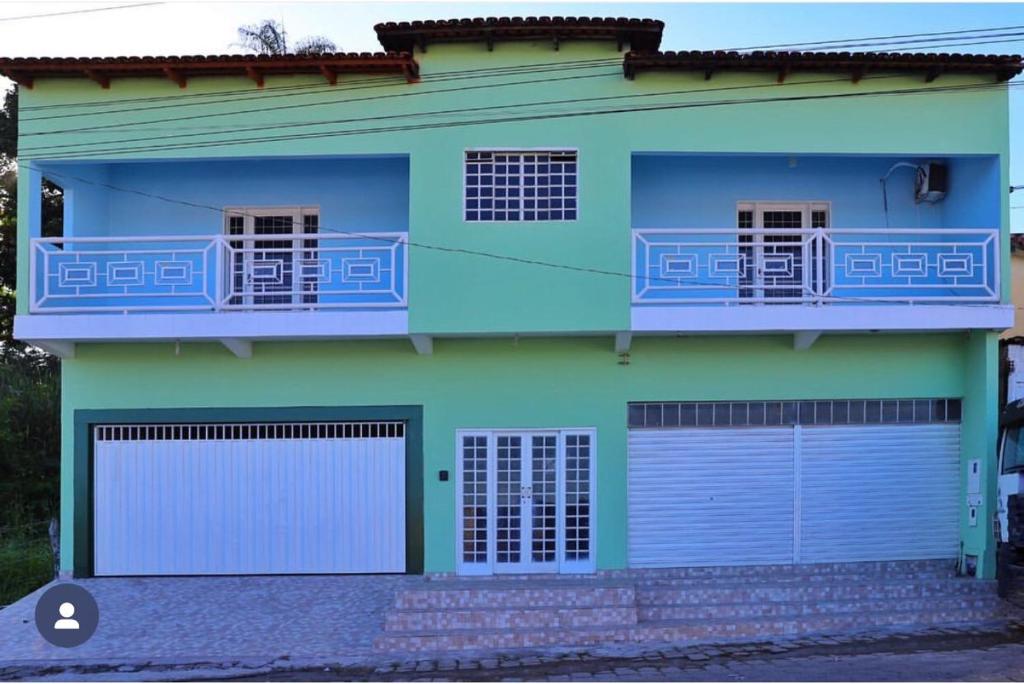 a blue and green house with two garage doors at casa verde hospedaria in Goiás