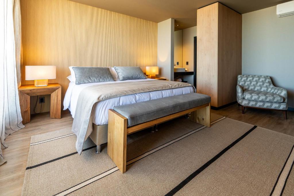 ein Schlafzimmer mit einem großen Bett und einem Stuhl in der Unterkunft Bravo Hotel in Punta del Este