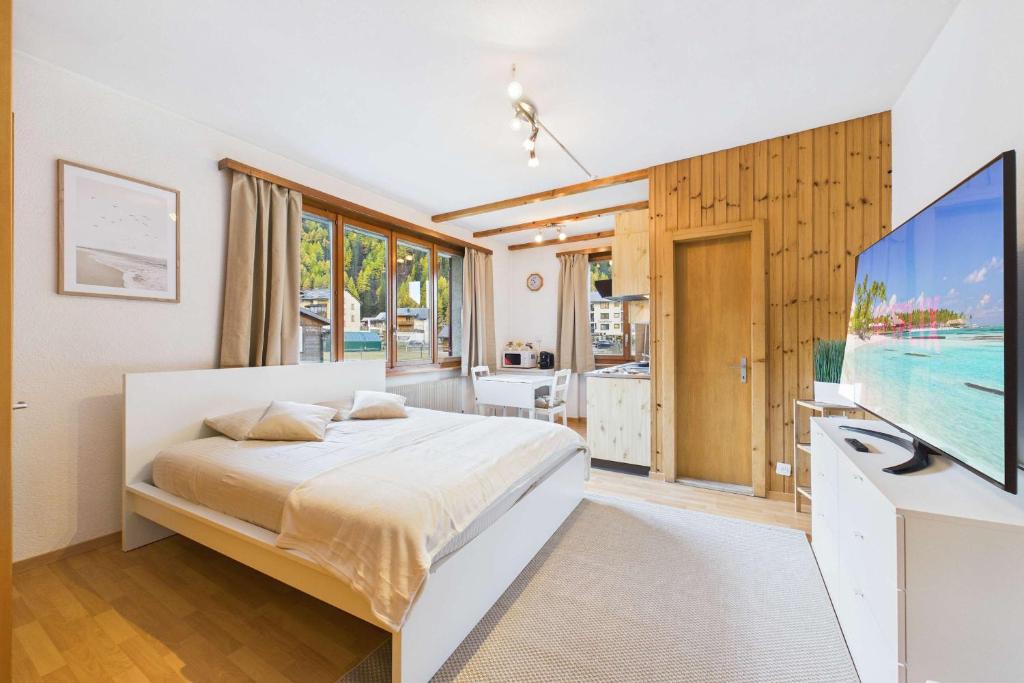 a bedroom with a bed and a flat screen tv at Comfortable studio with balcony and panoramic view in Saas-Grund