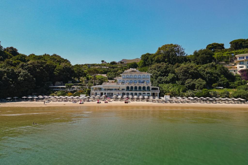 a beach with umbrellas and a building on the beach at Grand Hotel Il Ninfeo in Gaeta