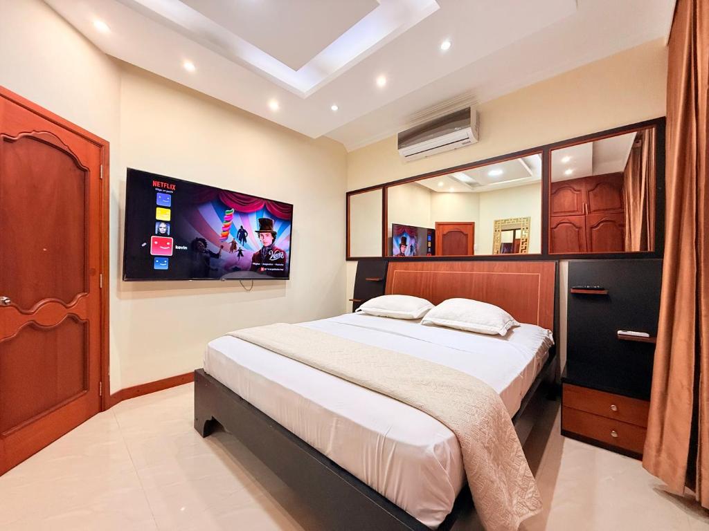 1 dormitorio con 1 cama grande y TV en la pared en Suite en Machala, en Machala