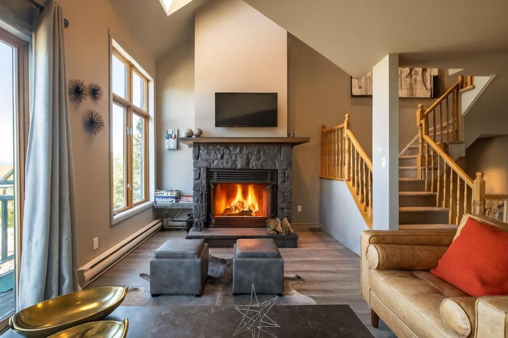 un salon avec une cheminée et un canapé dans l'établissement Tremblant Prestige - Clairiere 404, à Mont-Tremblant
