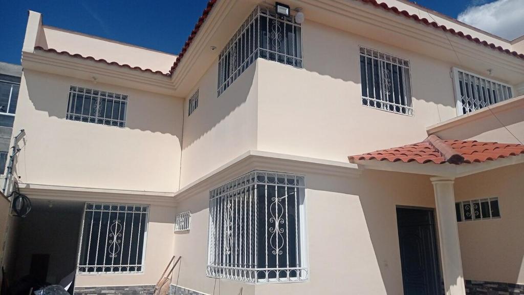a large white house with black barred windows at Casa en Atuntaqui in Atuntaqui
