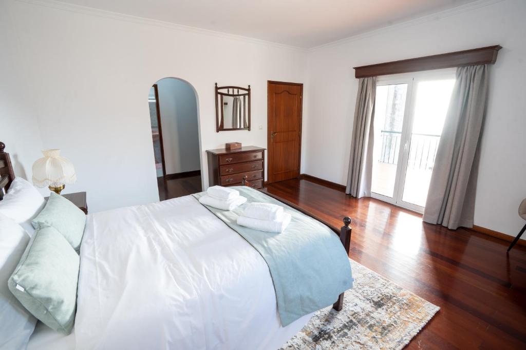 Un dormitorio con una cama blanca y suelo de madera. en Villa Mirage - by Madeira To Stay, en Arco da Calheta