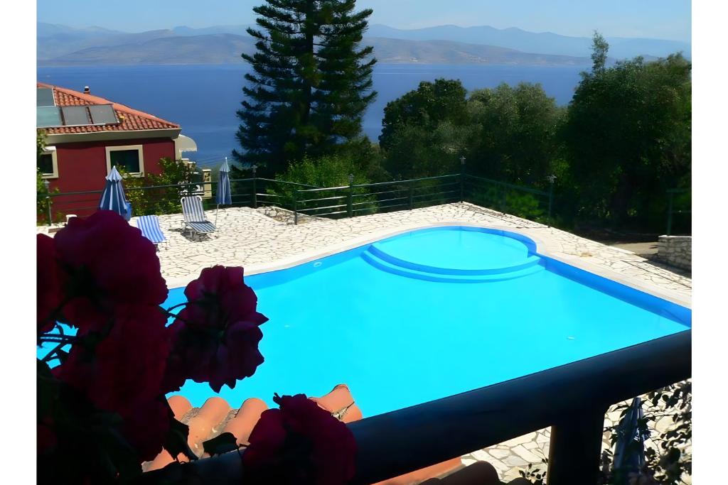 a blue swimming pool with a view of the water at Apraos Bay Hotel in Apraos