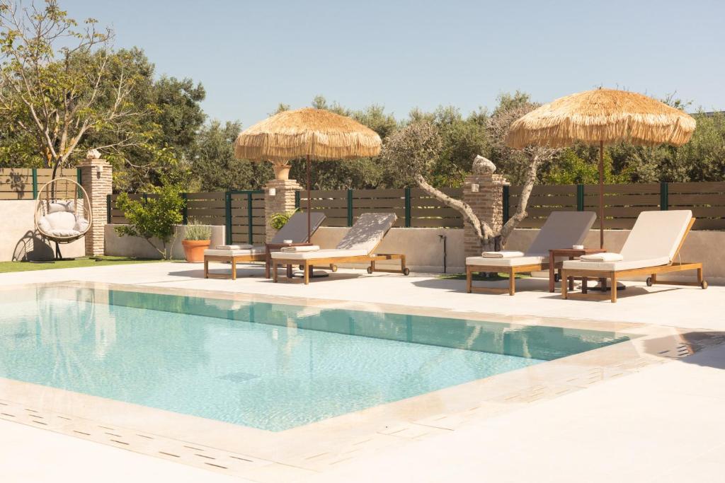 a swimming pool with lounge chairs and umbrellas at Porta Verde Luxury Residence, By TK Premium Stays in Laganas