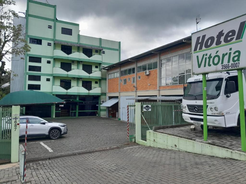 a hotel sign in front of a building with a car at Hotel Vitoria in Videira