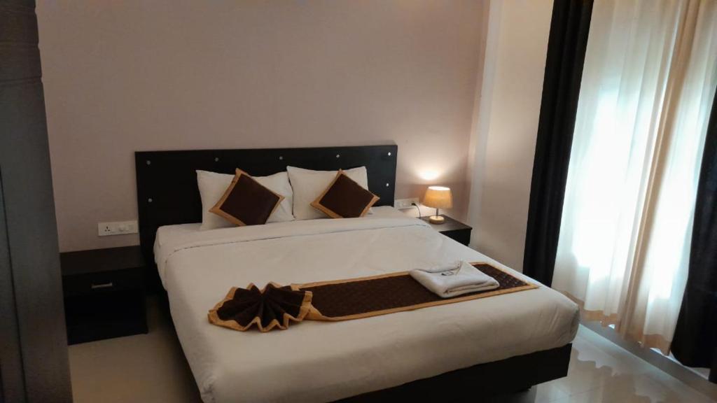 苏丹巴特利NEW MOUNT RESIDENCY的一间卧室配有一张白色大床和黑色床头板