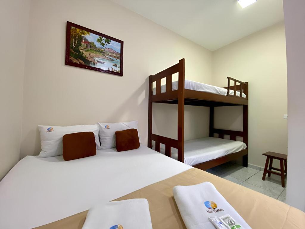 ein Schlafzimmer mit zwei Betten und einem Etagenbett in der Unterkunft Mar Suites Tenório in Ubatuba