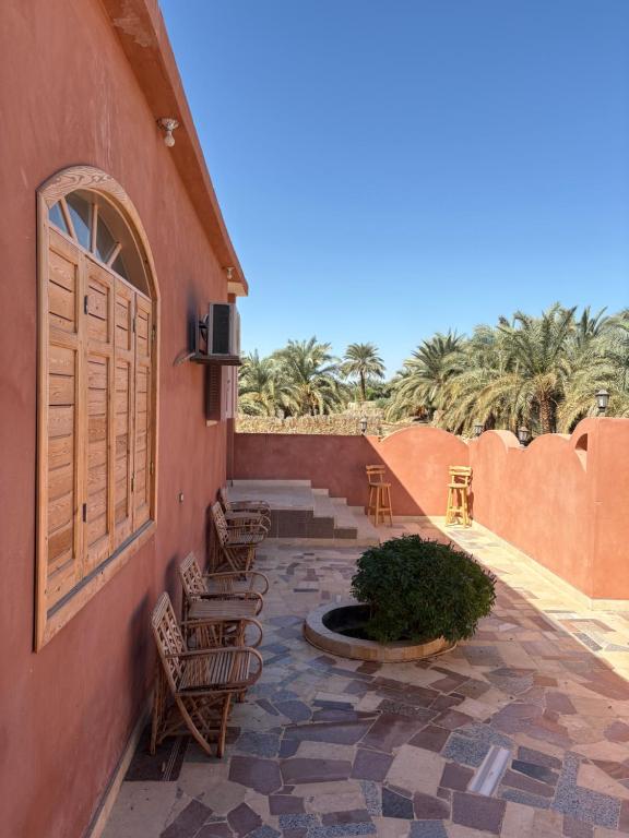 锡瓦Bakrine chalet的一个有椅子、门和棕榈树的露台