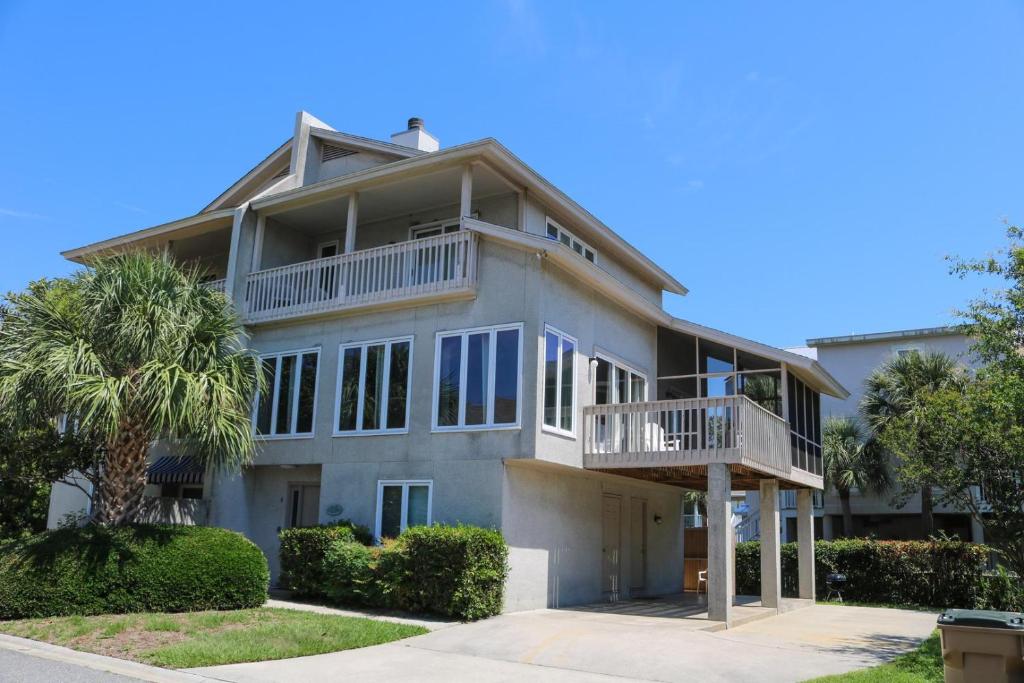 a large house with a balcony and a palm tree at Madelyn's Oceanview in Tybee Island