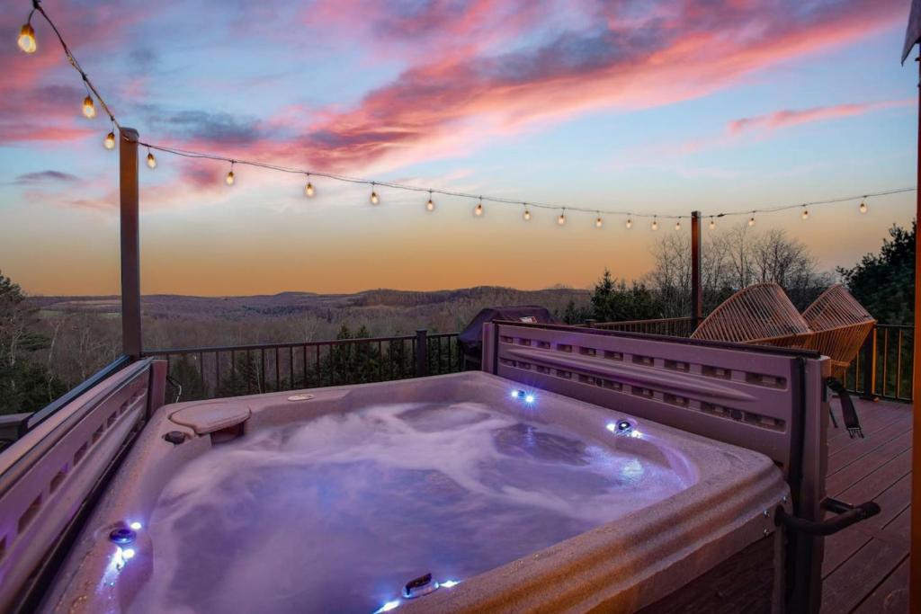 a jacuzzi tub on a deck with a sunset at Sunrise Sanctuary -Modern Yurt in Brookville