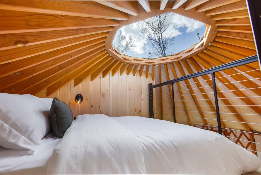 a room with a bed in a round window at Starlit Haven - Modern Yurt in Brookville