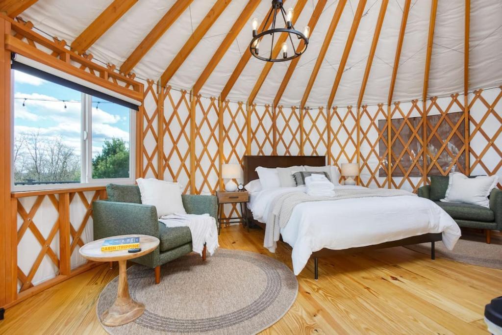 a bedroom with two beds and two chairs in a yurt at Horizon Hideout - Modern Yurt in Brookville
